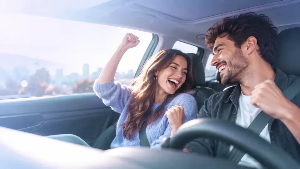 Two people celebrating in the front seats of a car